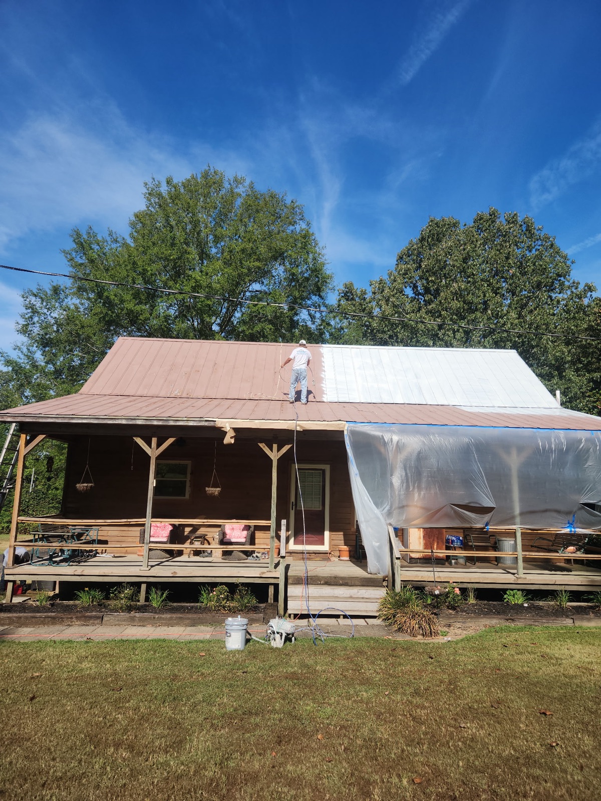 Dario painting a metal roof in Memphis — owner on the job